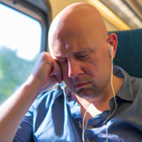 A middle aged bald man on a train crying while listening to music (1).jpg